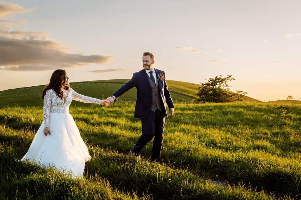 Natural, candid moment of the couple holding hands and walking through the Yorkshire countryside.